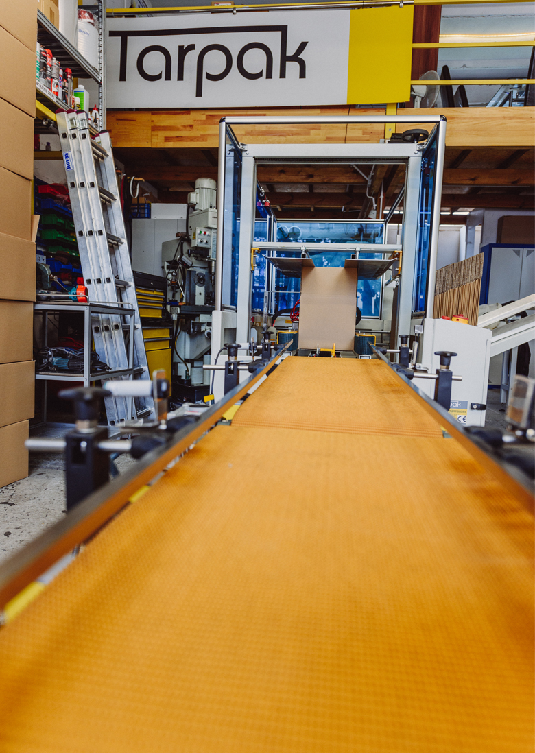 Zaklejarki kartonów przygotowujące opakowania zbiorcze do transportu w zakładzie produkcyjnym.